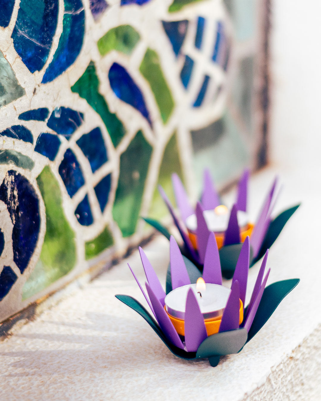 Decorative purple candle holders with candles on a mosaic background